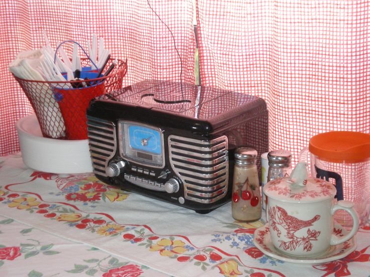 an old fashioned radio sitting on top of a table next to cups and vases