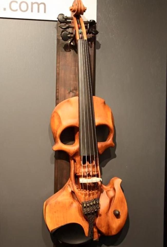 an orange violin hanging on the wall next to a piece of wood that has been carved into it