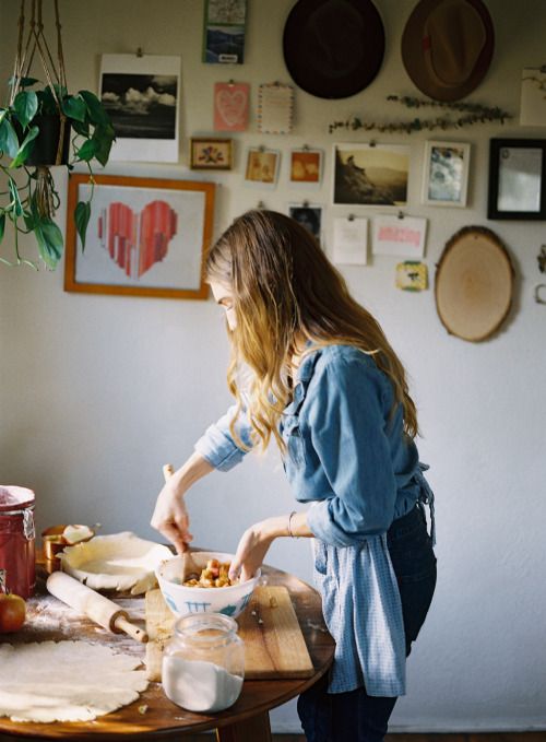 a woman standing in front of a counter cutting food on top of a wooden table