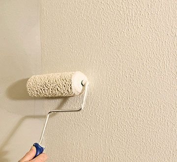 a person using a paint roller to paint a wall