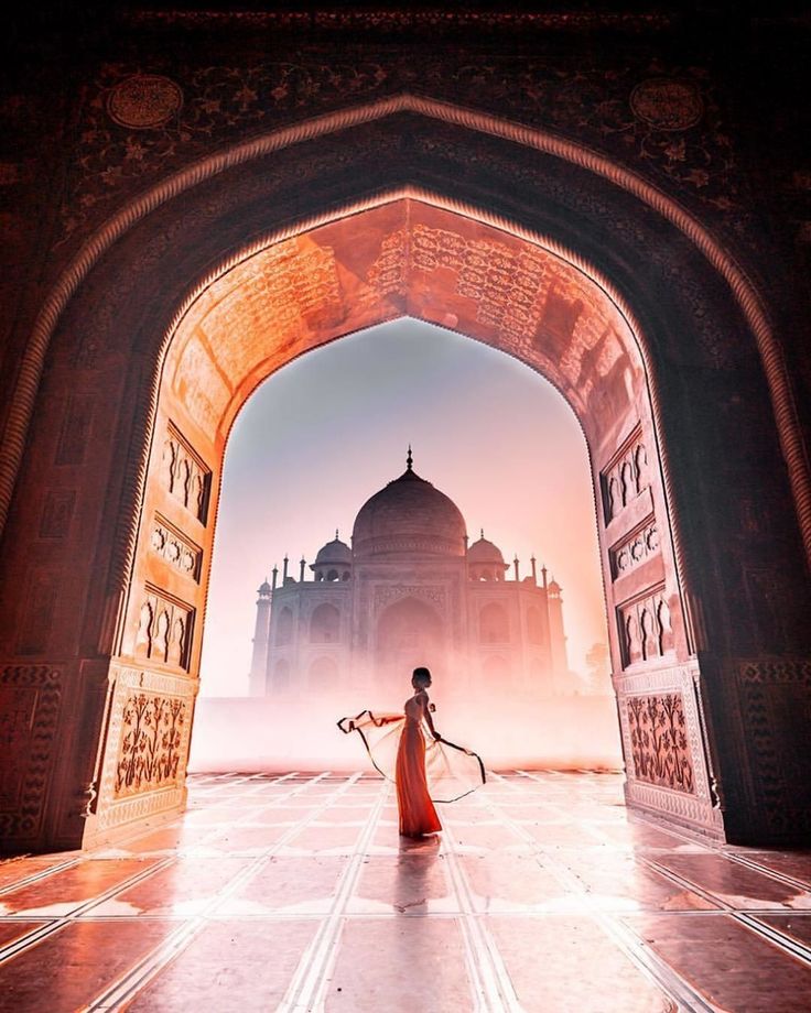 a woman holding a tennis racquet standing in front of an archway to a building