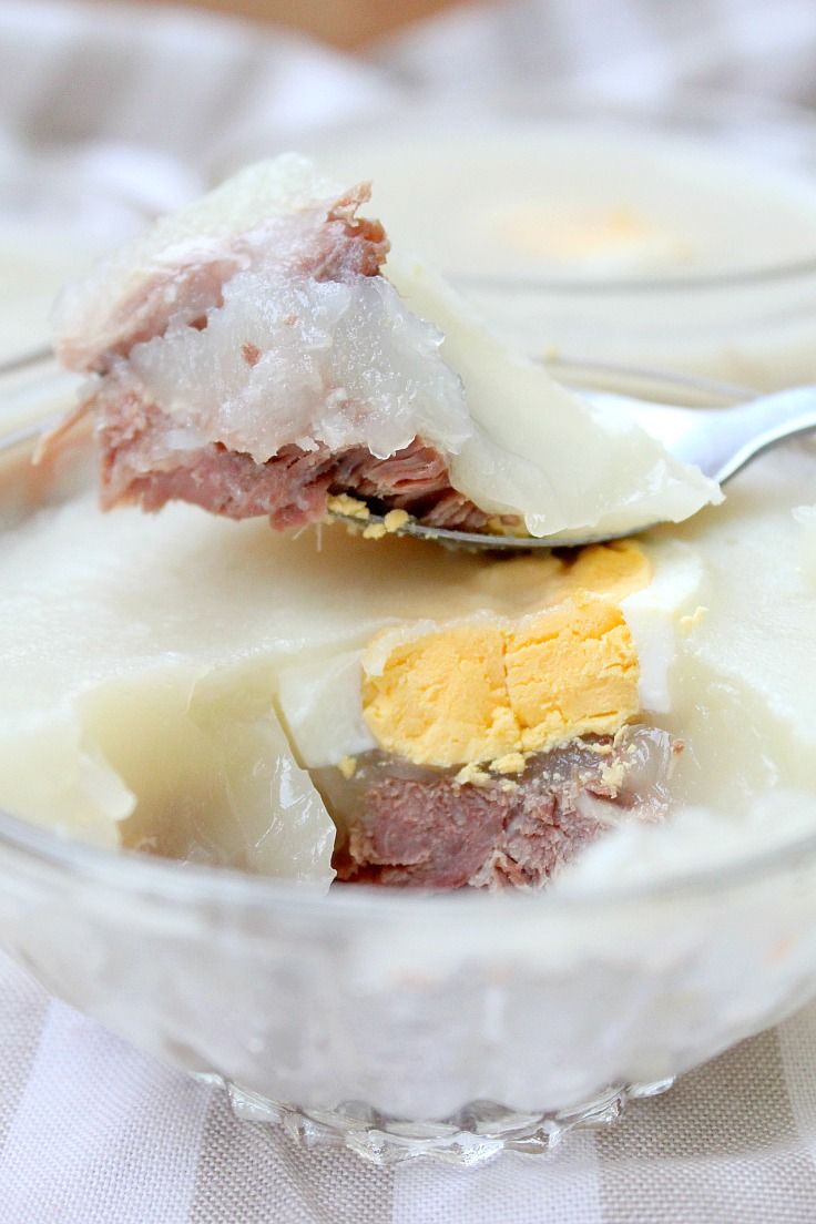 a bowl filled with pudding and butter on top of a white table cloth next to a spoon