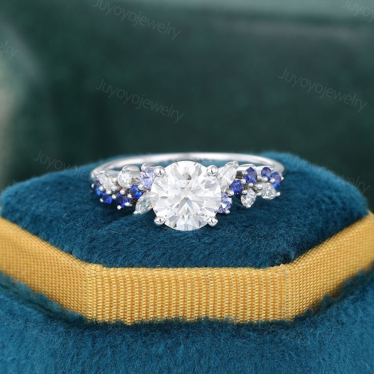 an engagement ring with blue sapphires and diamonds on display in a velvet cushion box