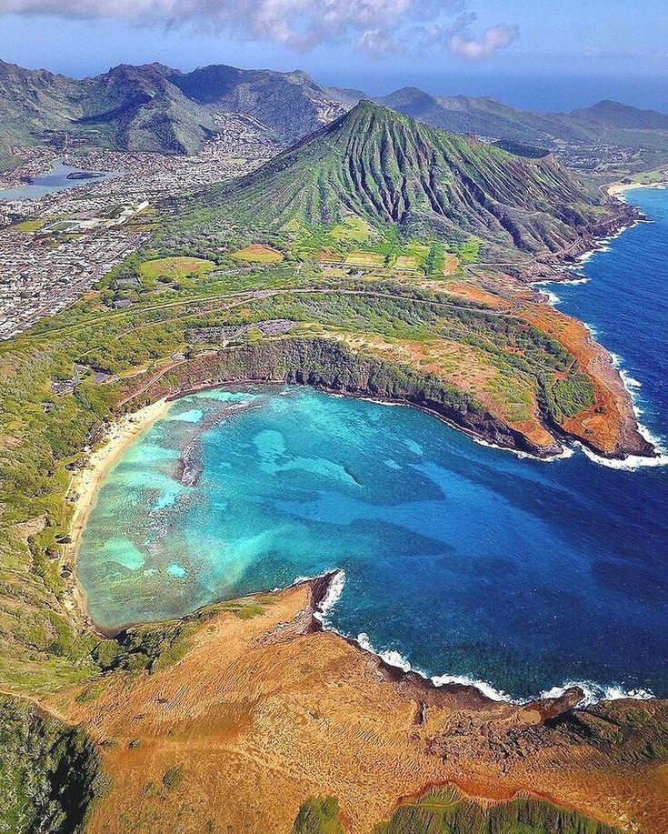 an aerial view of the ocean and landforms with mountains in the backgroud