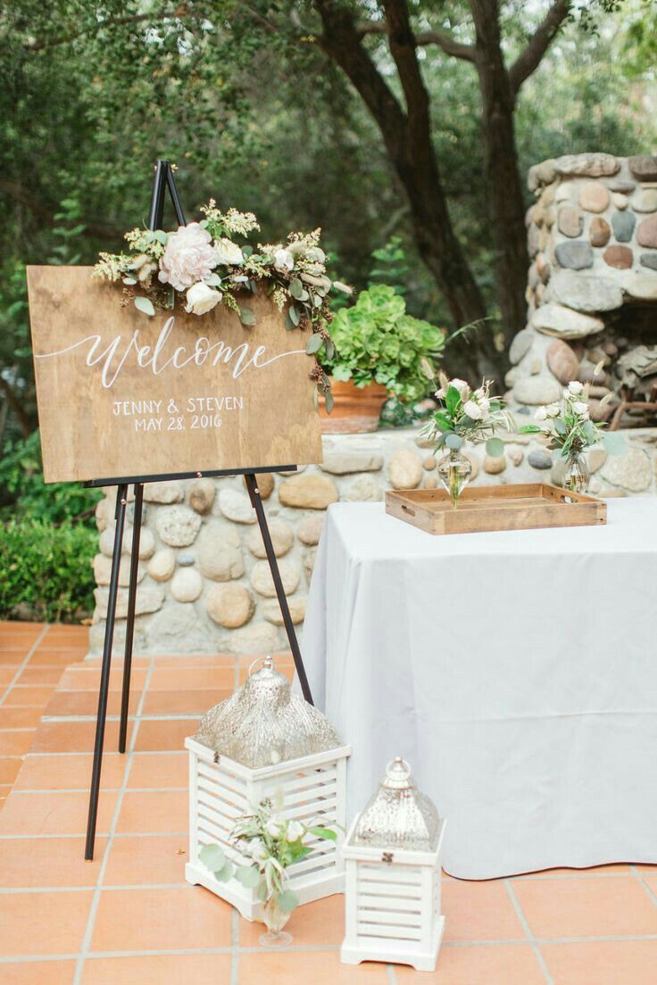 a sign that says welcome to the bride and groom on top of a table with flowers