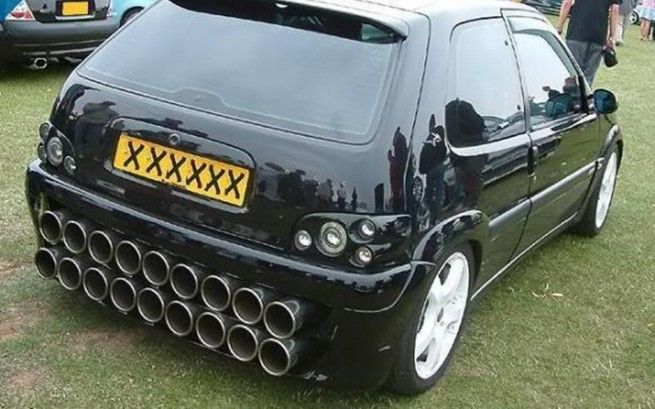 a black car parked on top of a grass covered field next to other cars and people