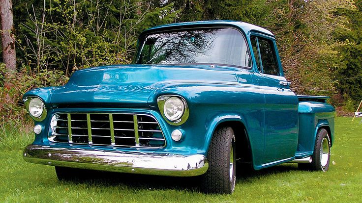 an old blue truck is parked in the grass