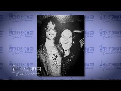 two women standing next to each other in front of a blue wall with the words weekly show on it