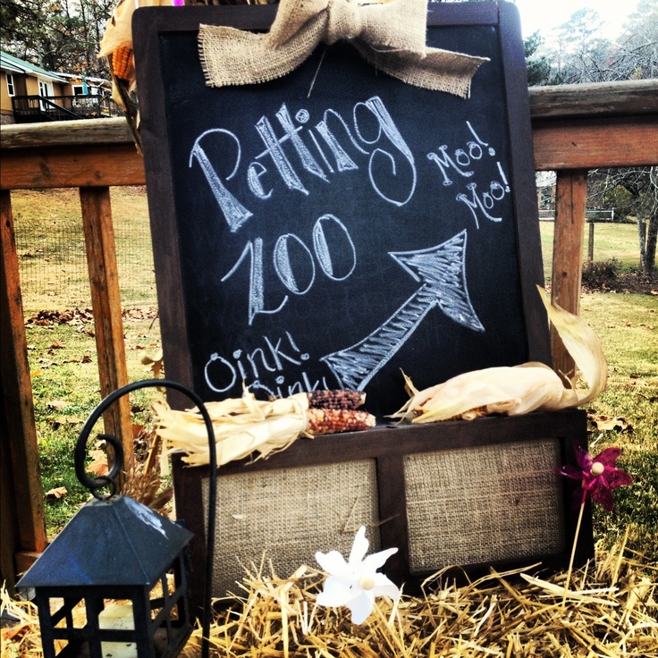 a chalkboard with writing on it sitting in hay next to a basket and lantern