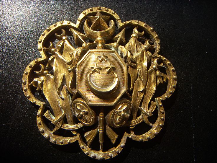 an ornate gold brooch on a black surface