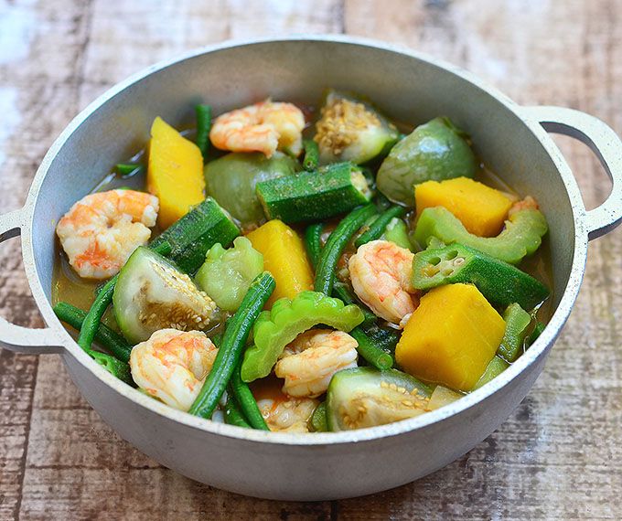 a pan filled with shrimp and veggies on top of a wooden table