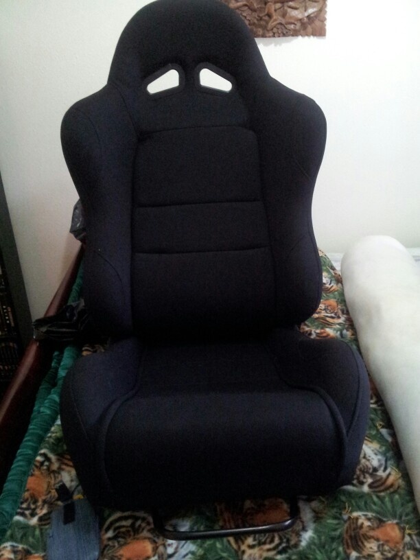 a black gaming chair sitting on top of a bed