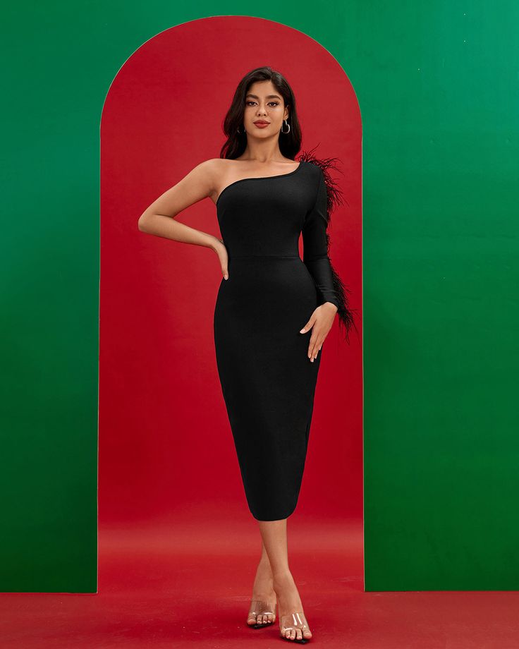 a woman standing in front of a green and red background wearing a black dress with one shoulder