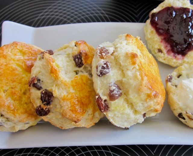 four scones on a plate with jam in the middle and one filled with biscuits