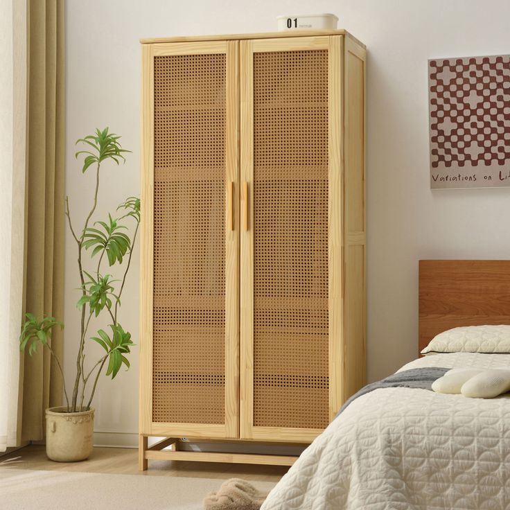 a bedroom with a bed and a wooden armoire next to a potted plant