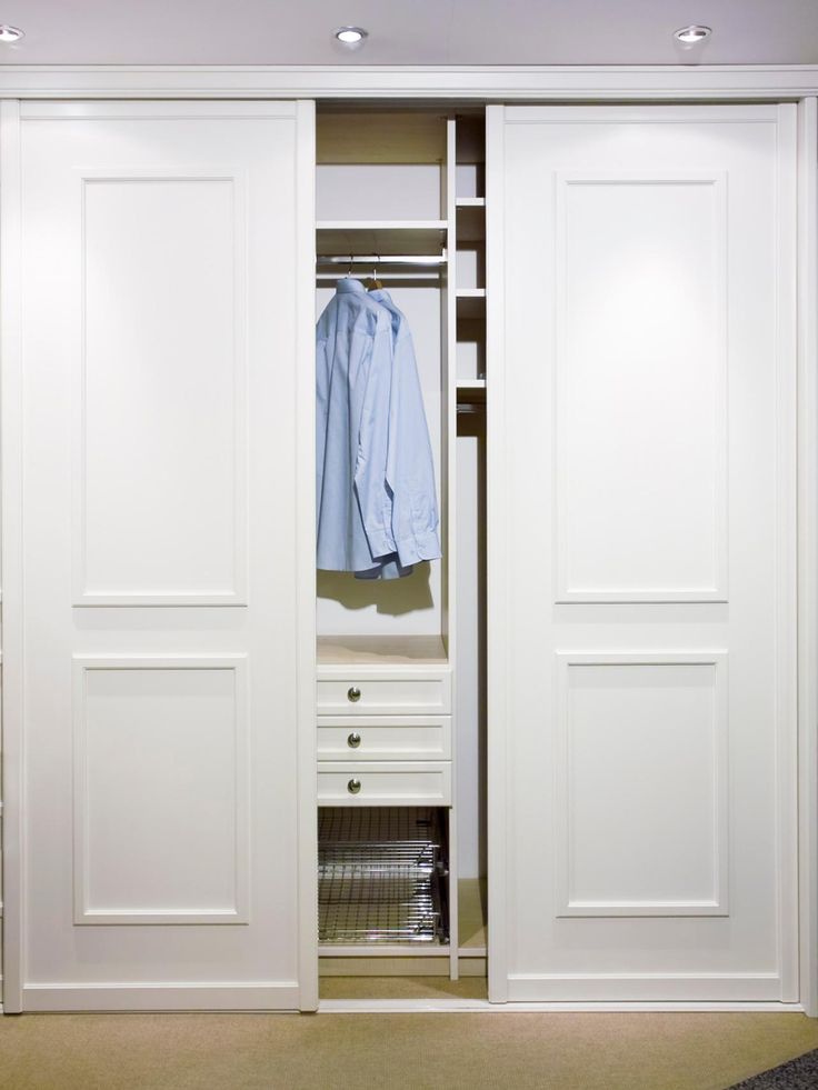 an open white closet with clothes on hangers