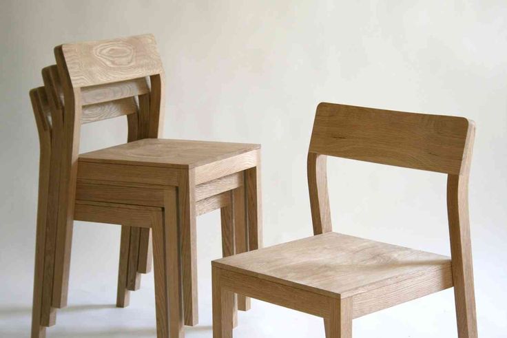 three wooden chairs sitting next to each other in front of a white wall and floor