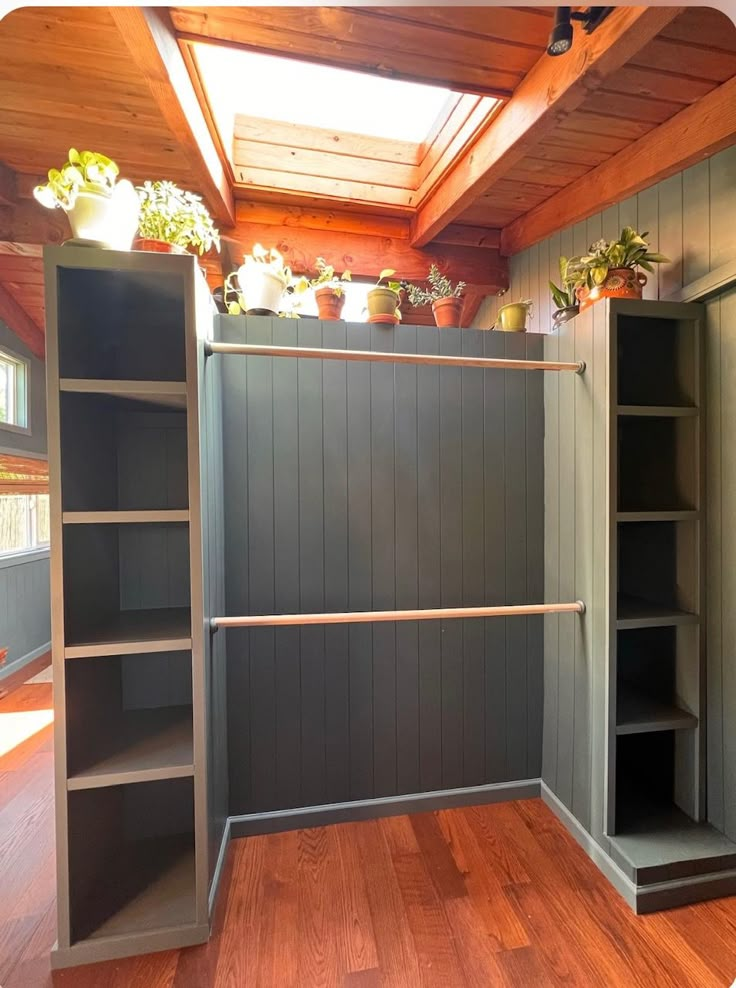 an empty room with shelves and potted plants on the top shelf, along with wooden flooring