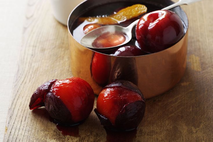 there are plums in a pot and spoon on the table