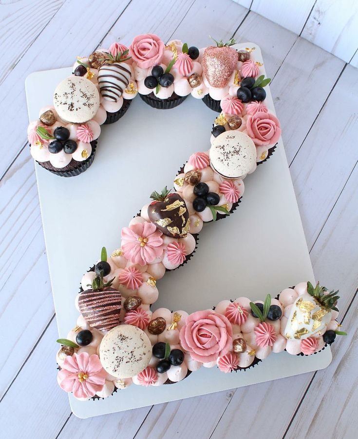 a letter made out of cupcakes on top of a white board with flowers