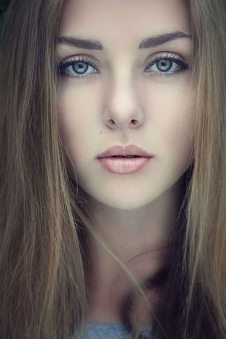 a woman with long hair and blue eyes is posing for the camera, her head tilted to the side