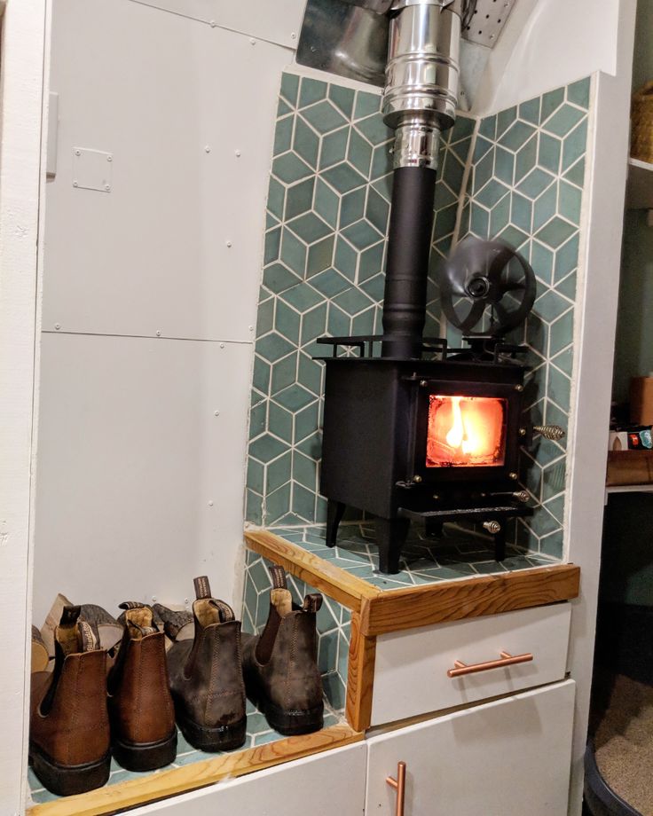 several pairs of shoes are lined up in front of an open wood stove with a heater on top