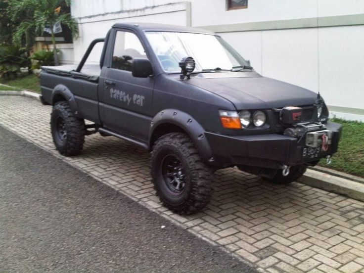 a gray pick up truck parked on the side of a road next to a building