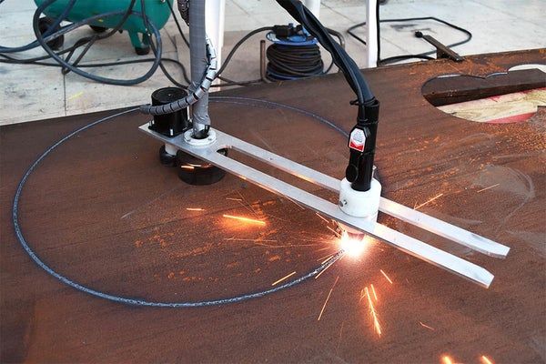 welders are cutting metal on a table with some sparks in the air behind them