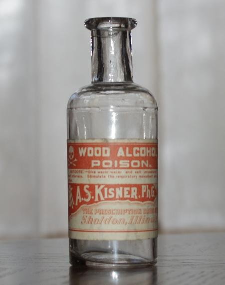 an old glass bottle sitting on top of a wooden table next to a white wall