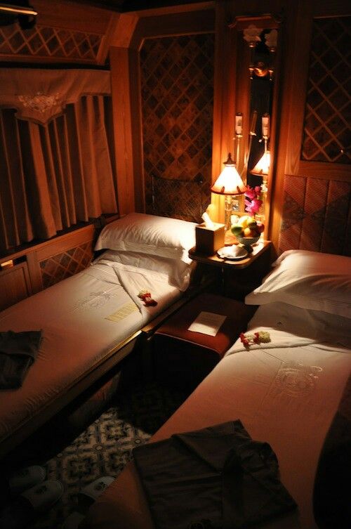 two twin beds in a room with wooden paneling and lamps on either side of them