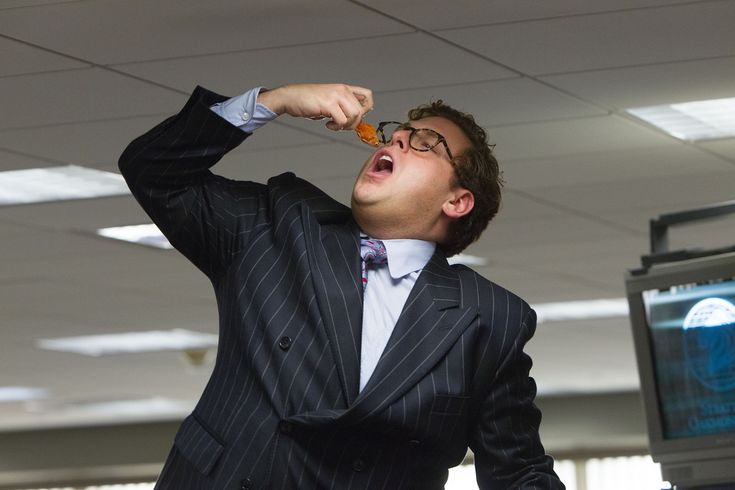 a man in a suit is eating something with his mouth wide open while looking up into the sky