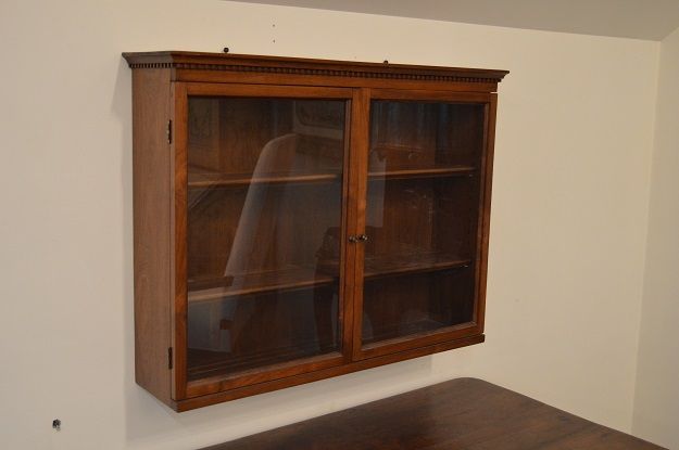 a wooden cabinet sitting on top of a wooden table next to a white walled wall