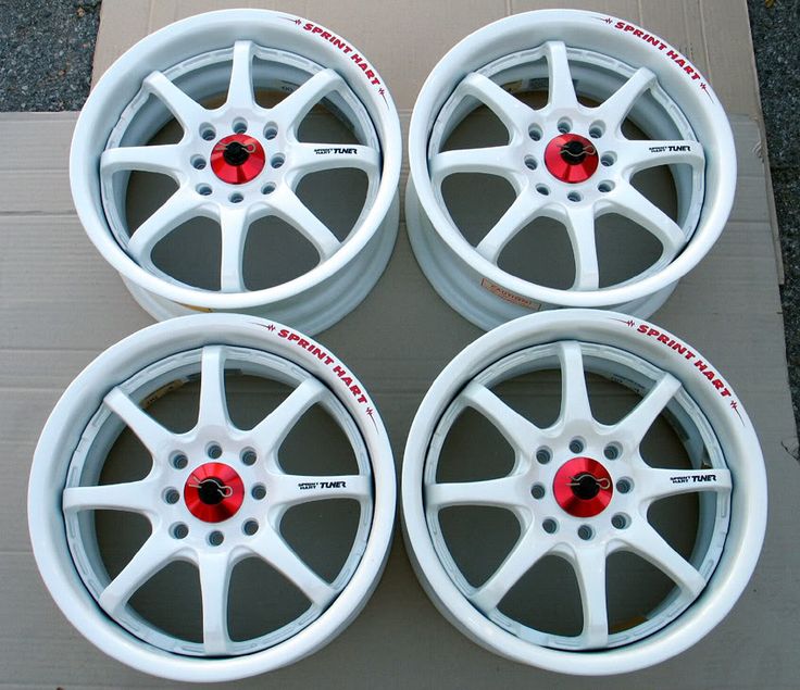 four white rims with red spokes are sitting on a cardboard box next to each other