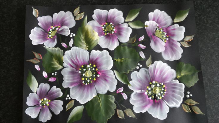 an image of flowers painted on a piece of black paper with white and pink petals