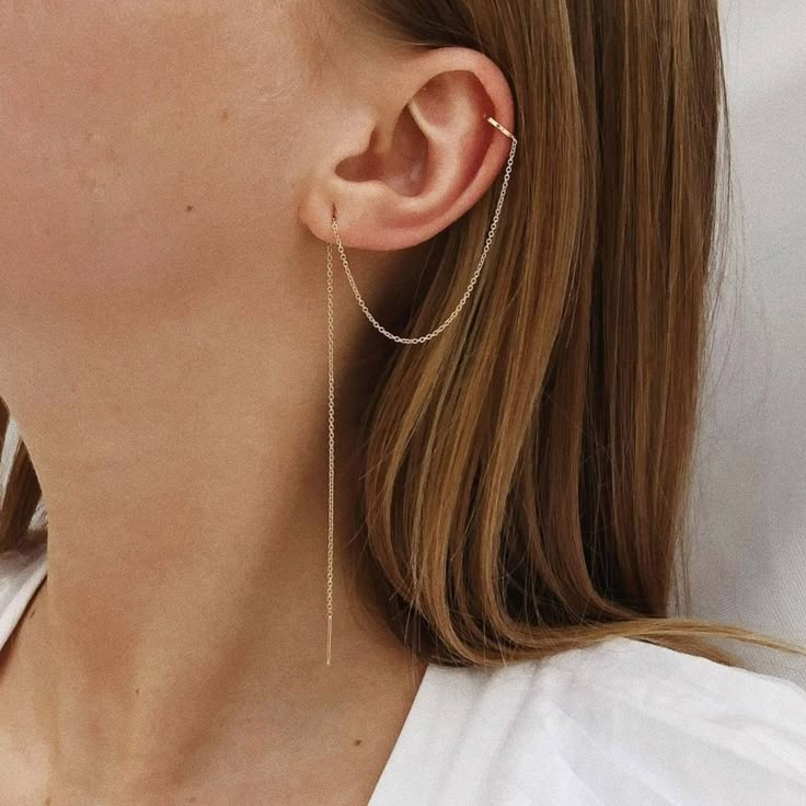 a close up of a person wearing some kind of earring with long chain attached to it