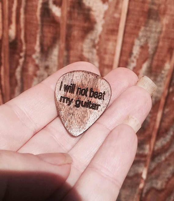 someone is holding a wooden guitar pick that says i will not beat my guitar