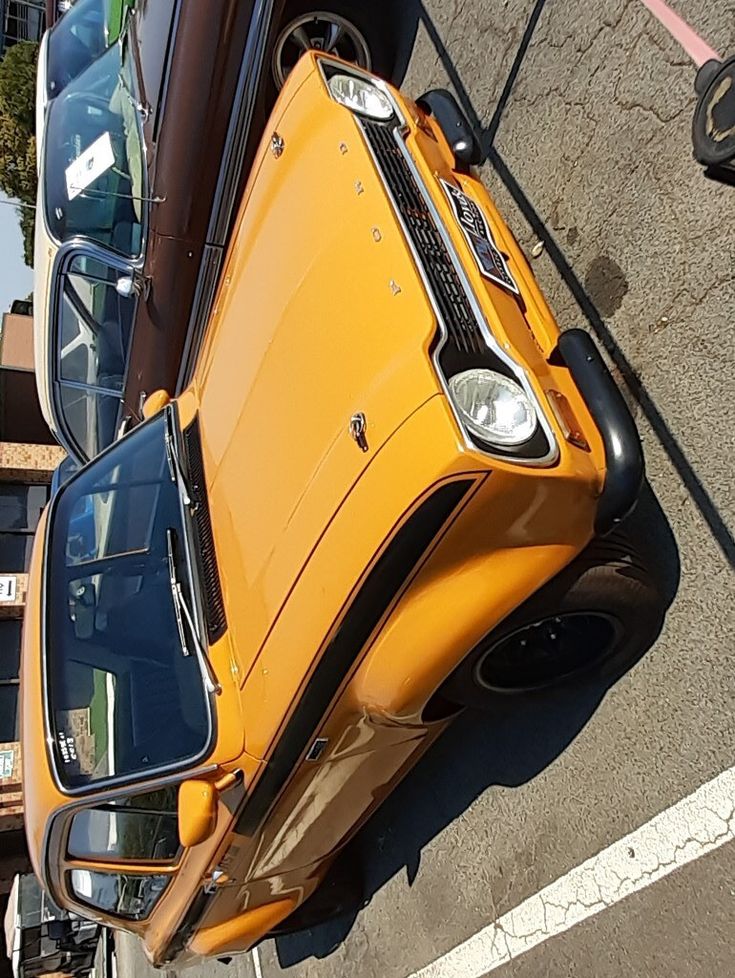 the front end of a yellow car parked in a parking lot