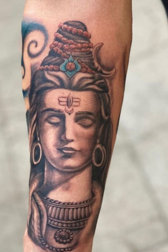 a tattoo on the leg of a person with a buddha head and earrings