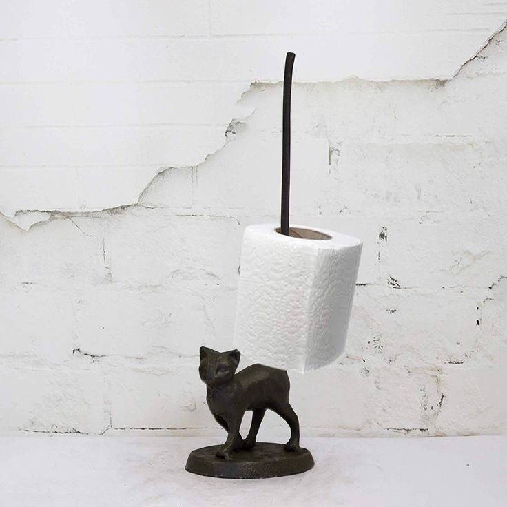 a toilet paper holder with a cat figurine next to it