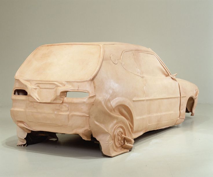 a car made out of clay sitting on top of a white floor next to a wall