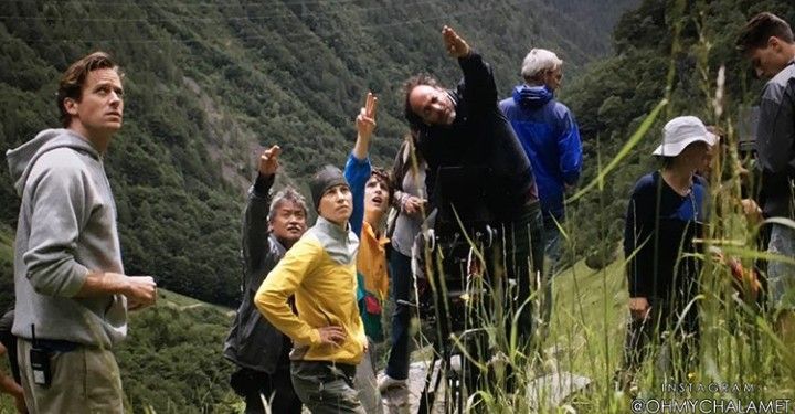 a group of people standing on top of a lush green hillside