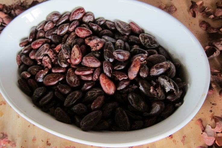 a white bowl filled with lots of dark colored beans on top of a wooden table