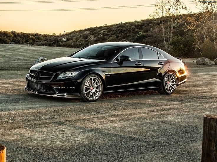 a black car parked on the side of a dirt road