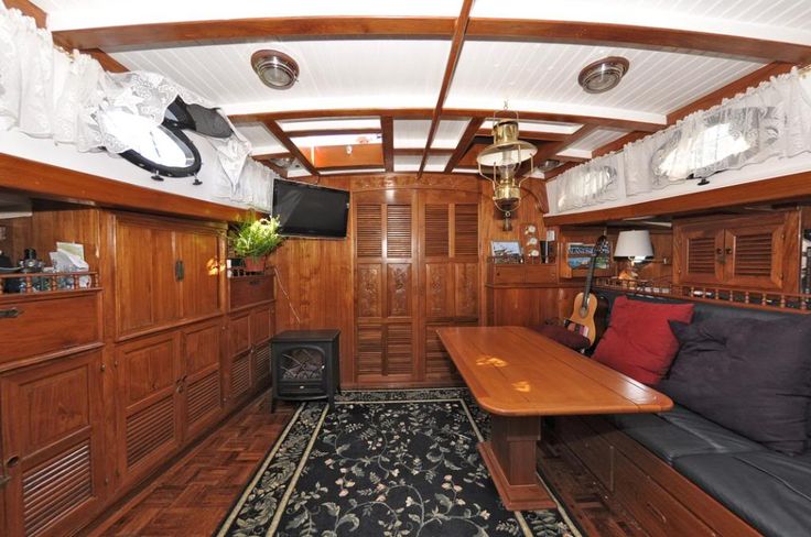 the inside of a boat with wood paneling and black couches, wooden tables and chairs