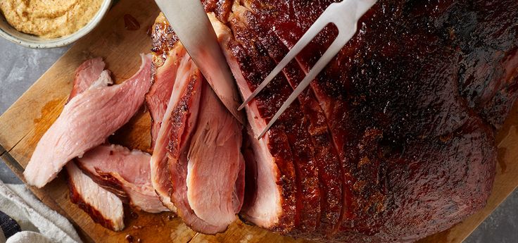 the ham is sliced and ready to be cooked on the cutting board with knifes