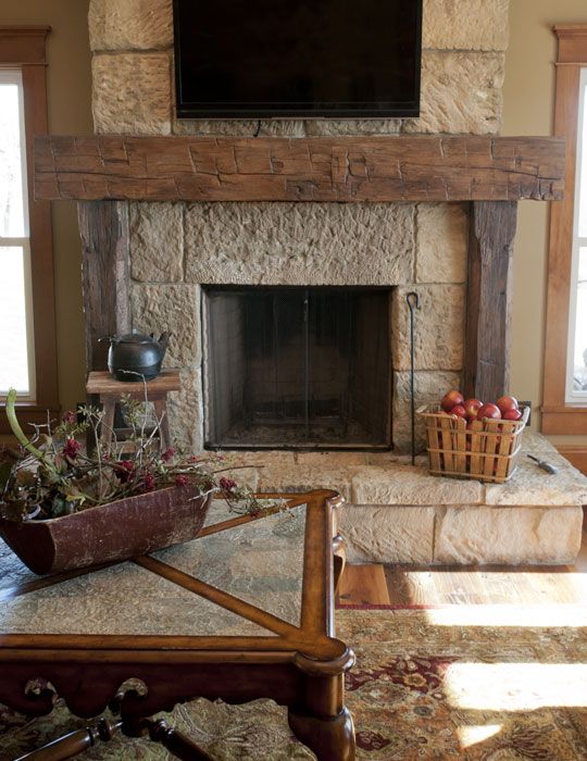 a living room with a stone fireplace and large screen tv on the wall above it