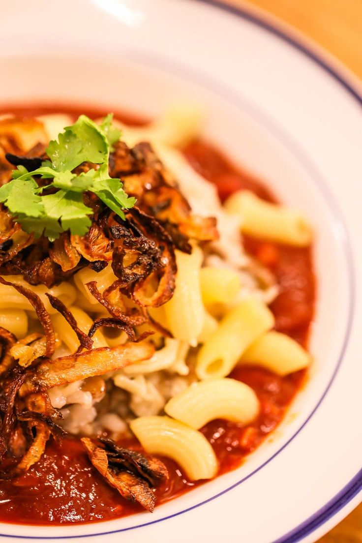 a bowl filled with pasta and sauce on top of a wooden table