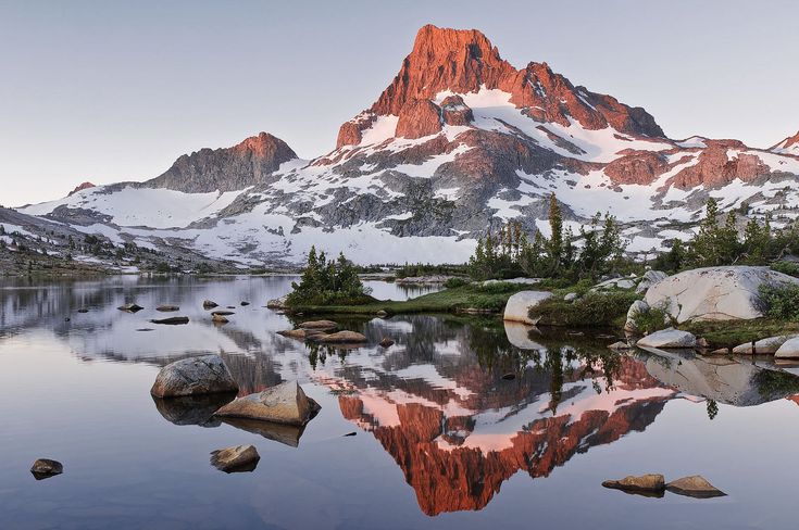 the mountains are reflected in the still water