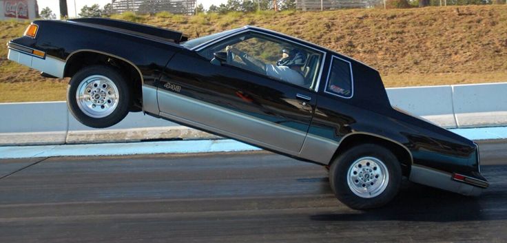 a black car that is upside down on the ground with it's hood up