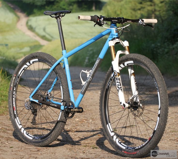 a blue and white bike parked on top of a dirt road